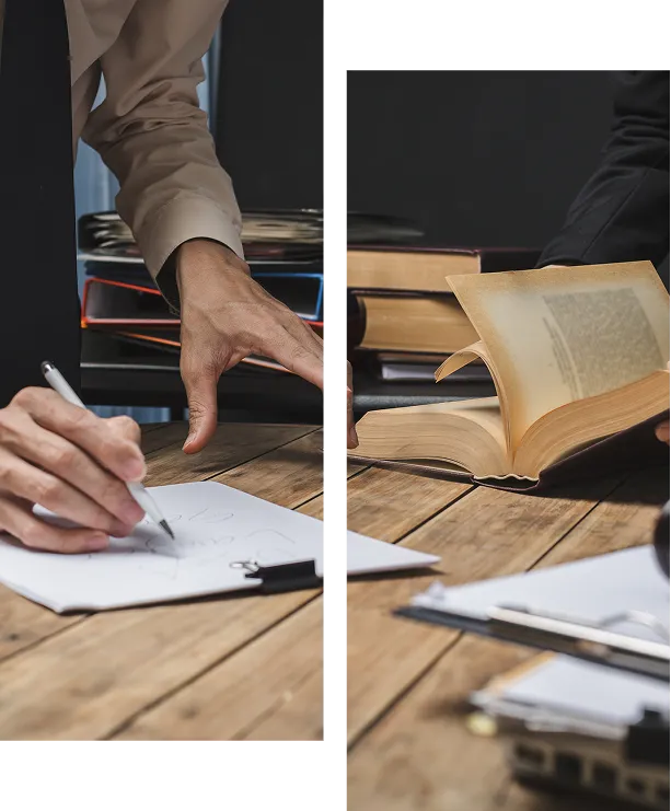 Hands writing on a clipboard beside stacked books, paired with hands opening a thick old book on a rustic wooden desk.