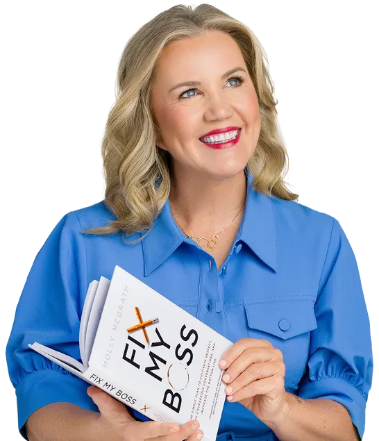 Molly, a smiling blonde woman in a blue collared shirt, holds her book "Fix My Boss" with both hands.