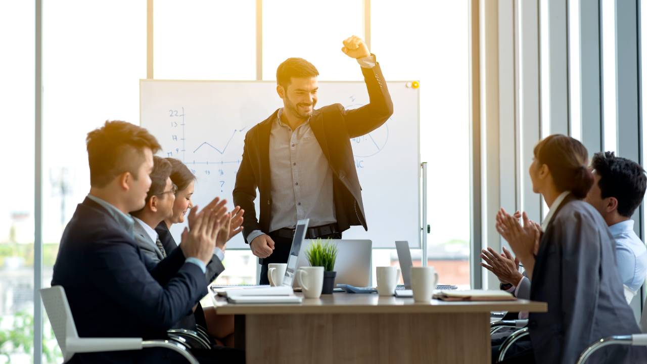 Business team applauding while boss or team leader raise their fists up showing confident after successful in office.